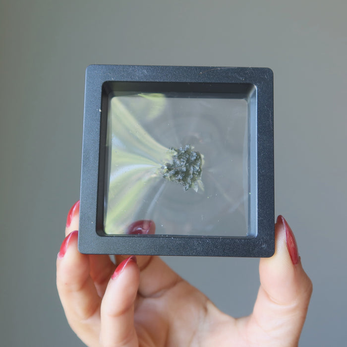green moldavite specimen in case