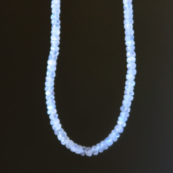 Rainbow Moonstone necklace with small blue beads on a black background