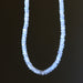 Rainbow Moonstone necklace with small blue beads on a black background