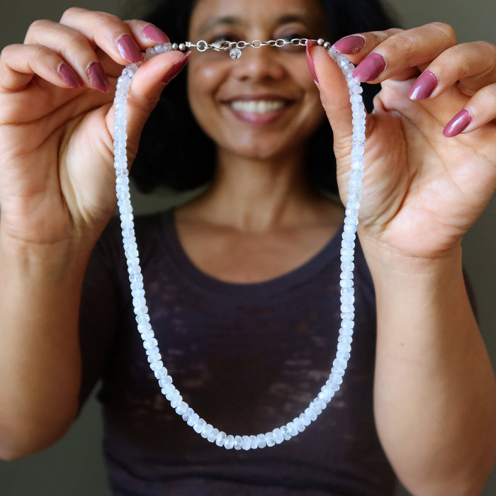 Person holding a beaded Rainbow Moonstone necklace with a blurred background