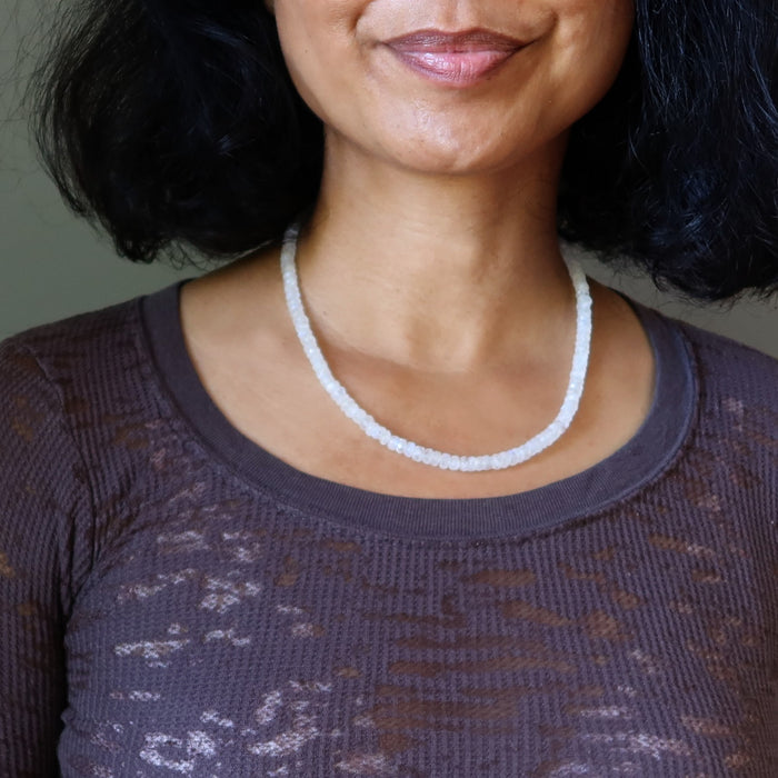 Woman wearing a white Rainbow Moonstone necklace with a neutral background
