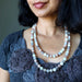 Woman wearing a layered Moonstone Necklace with a textured dark top against a neutral background