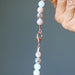 Beaded Moonstone Necklace with a clasp held by a hand against a gray background