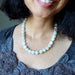 Close-up of a person wearing aWhite Moonstone Necklace with a dark gray top.