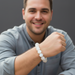 Man wearing a white beaded moonstone bracelet on his wrist, smiling.