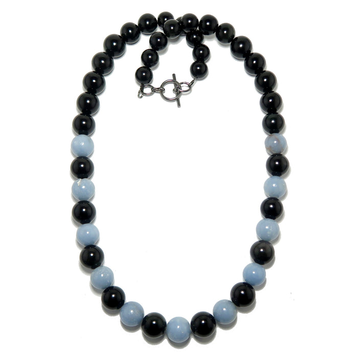 Necklace with alternating black obsidian and light blue angelite beads on a white background