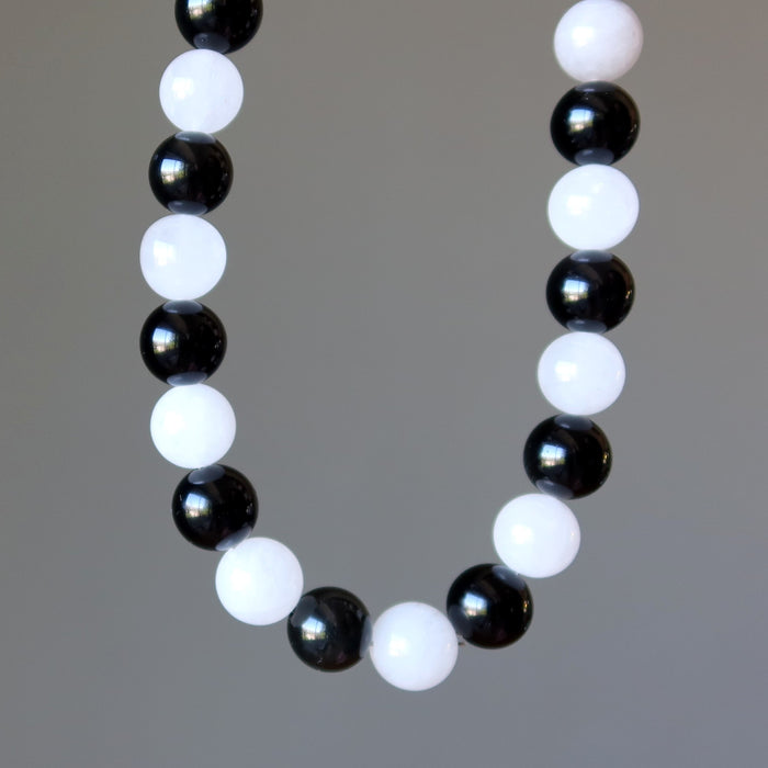 Rainbow Obsidian Snow Quartz necklace with alternating black and white beads on a gray background