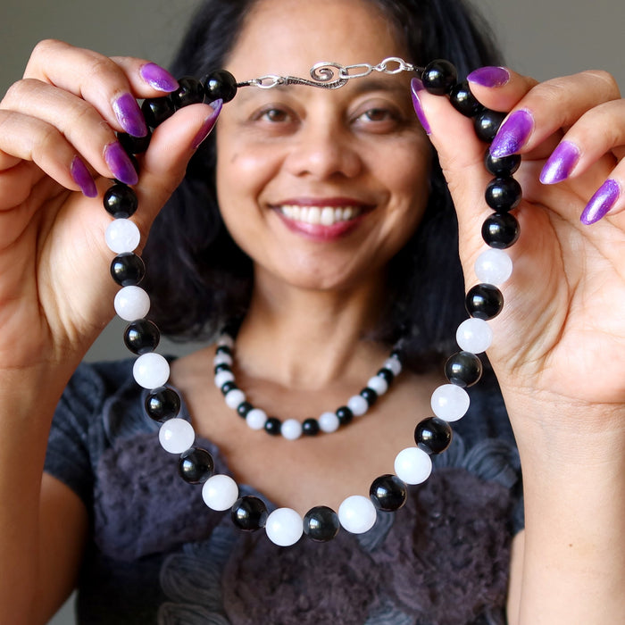 Woman holding a black, white, and silver beaded Rainbow Obsidian Snow Quartz necklace 