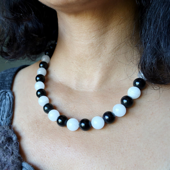 Rainbow Obsidian Snow Quartz necklace with black and white beads worn by a person