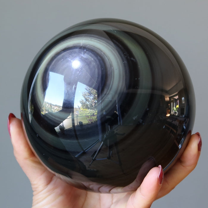 rainbow obsidian sphere in hand