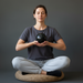 Person meditating with a rainbow obsidian sphere in hands on a gray background