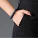Person wearing a blue beaded obsidian bracelet on a plain background