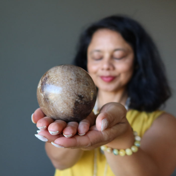 Woman holding a large stone opal ball with a blurred background