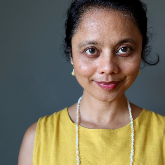 Woman wearing yellow Opal earrings with a plain background