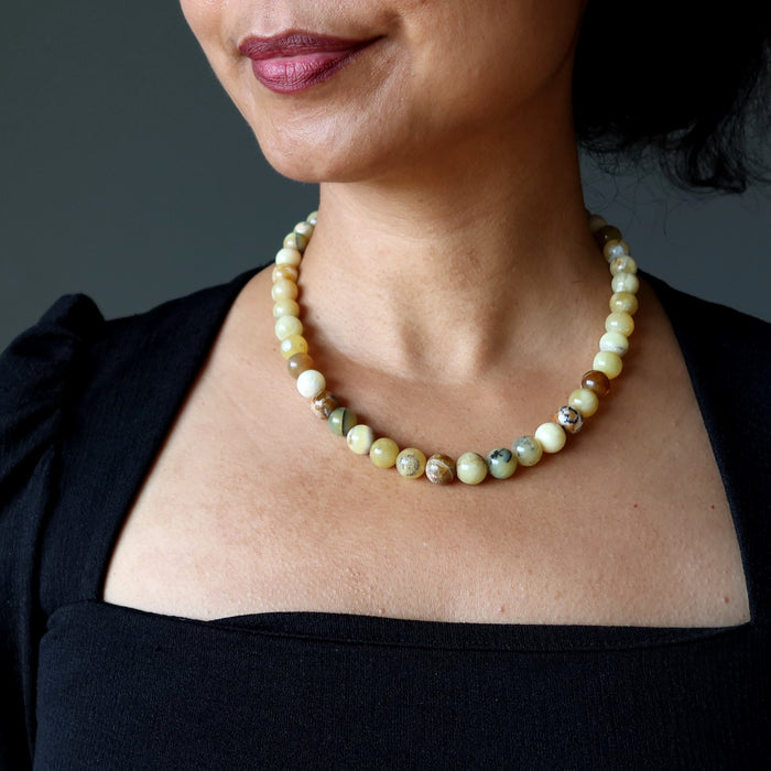Close-up of a person wearing a beaded Opal necklace against a dark background