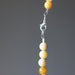 Opal necklace with yellow beads and a silver clasp on a gray background