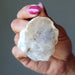 Hand holding a rough Opal crystal rock against a neutral background