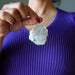 Person holding a Opal pendant against a purple shirt