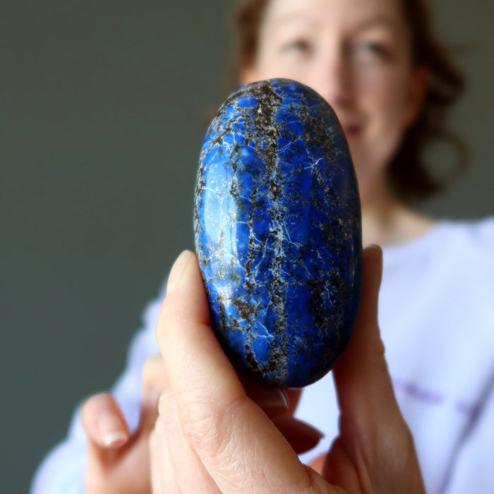 Person holding a blue Lapis stone with a blurred background