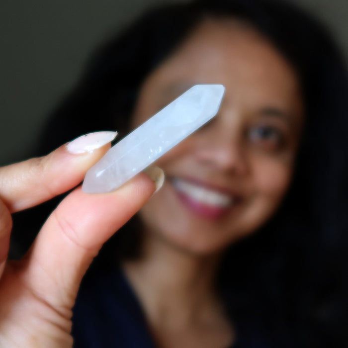 Person holding a clear quartz doubleterminated  with a blurred background