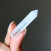 clear quartz doubleterminated crystal held in a hand against a dark background