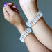 Clear Quartz bracelets on a person's wrist against a gray background