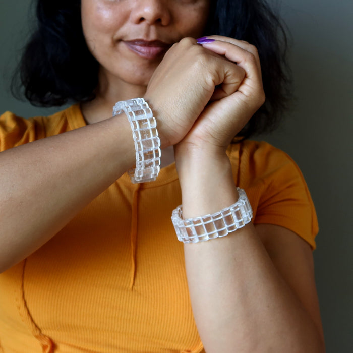 Person wearing two clear Clear Quartz bracelets on a neutral background