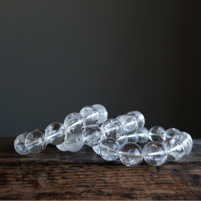 Clear beaded quartz bracelet on a dark surface with a dark background
