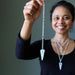 woman wearing and holding clear quartz pendulum necklaces