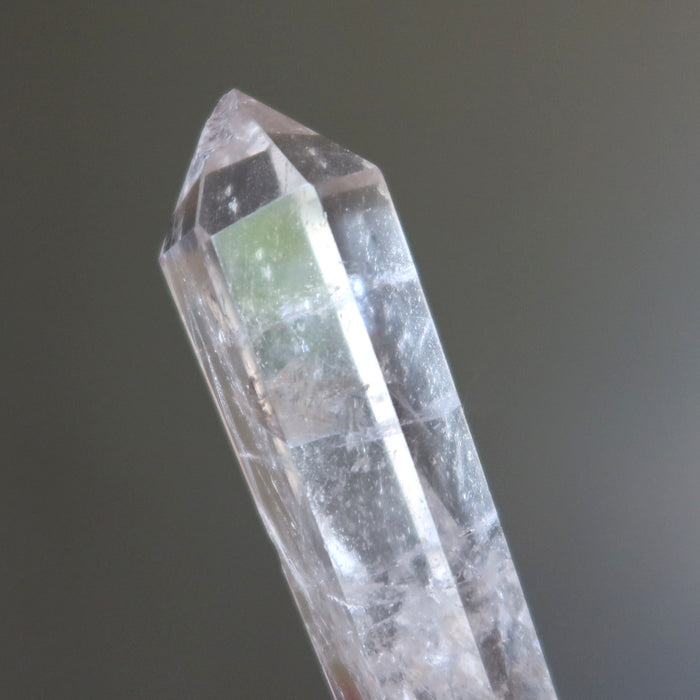 Clear quartz crystal wand with green interior on a dark background
