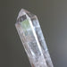 Clear quartz crystal wand with green interior on a dark background