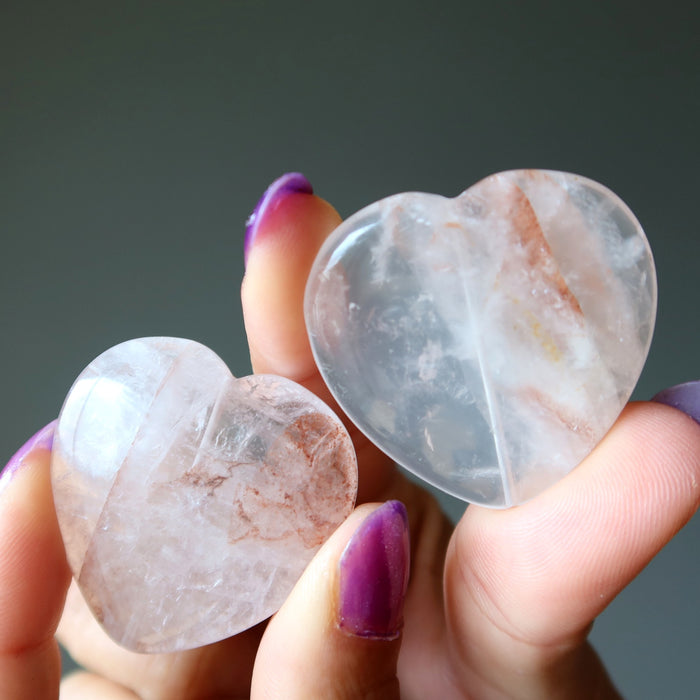 Hand holding two smooth, polished quartz stones against a dark background