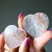Hand holding two smooth, polished quartz stones against a dark background