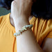Person wearing a Rutilated Quartz bracelet with small stones, against a blurred background