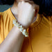 Person wearing a yellow Rutilated & Clear Quartz beaded bracelet on an orange shirt