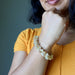 Person wearing a yellow Rutilated & Clear Quartz beaded bracelet on an arm with a blurred background