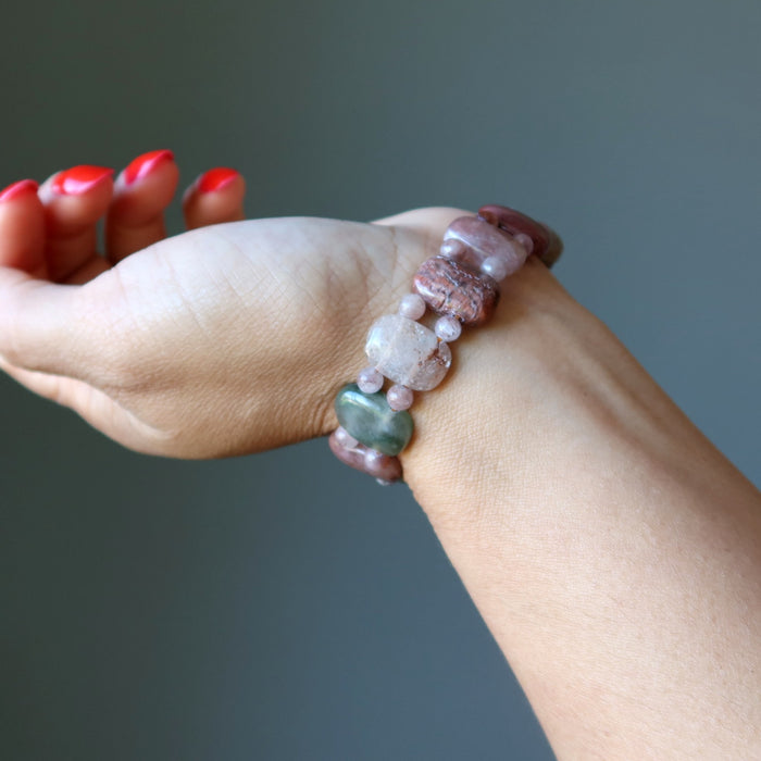 Hand wearing a colorful beaded bracelet against a neutral background