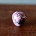 Heart-shaped pink Rhodonite apple stone on a wooden surface