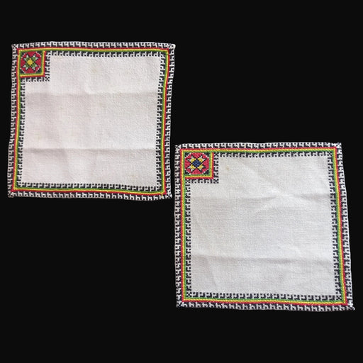 Two vintage white napkins from Bereg Hungary Europe with embroidered borders on a black background