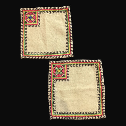 Two square embroidered fabric patches with geometric patterns from bereg hungary central europe on a dark background 