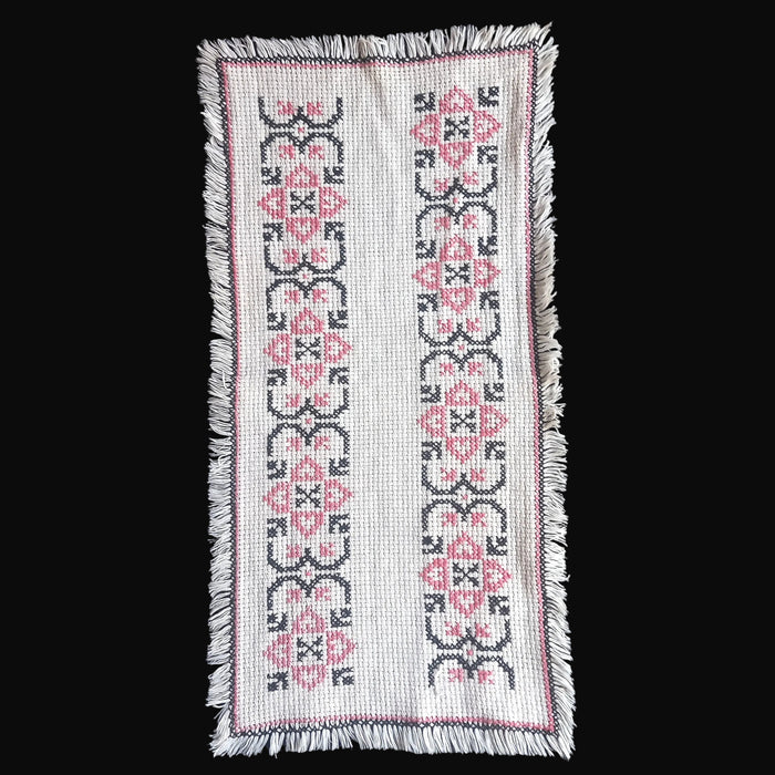 Hungarian Bereg folk art handmade cross stitch with pink and black pattern on a white background