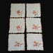 Set of six brown embroidered doilies from Hungary with floral designs on a dark surface.