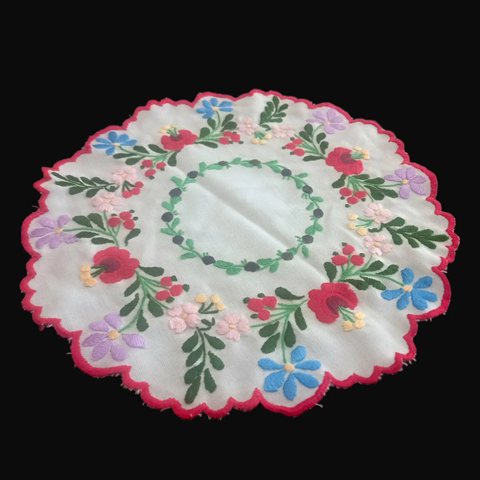 Decorative hungarian kalocsa coloful wreath doily with floral patterns on a black surface