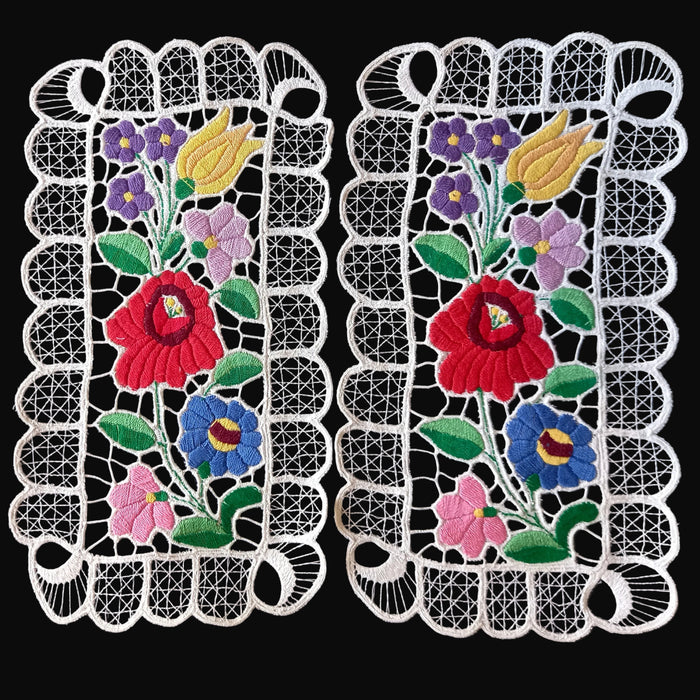 Pair of vintage hungarian kalocsa lace doilies with floral designs on a black background