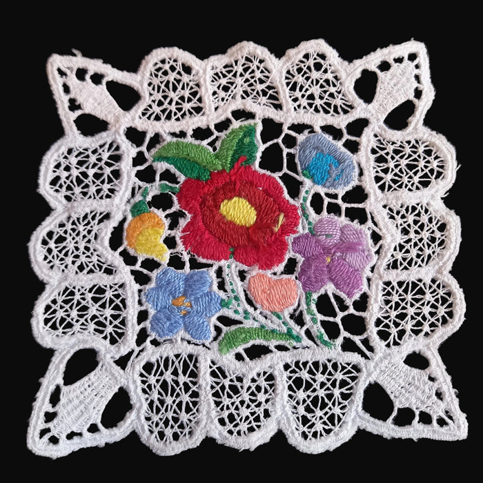 Decorative Hungarian Richelieu Kalocsa doily with embroidered flowers on a black background