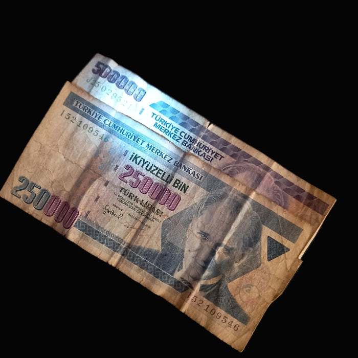 Worn Turkish lira banknote on a dark surface