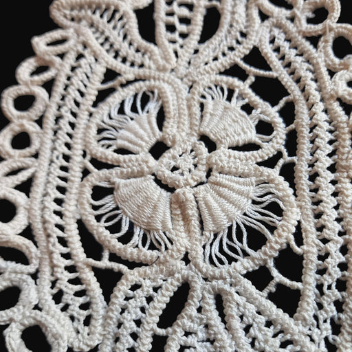 Close-up of intricate lace fabric with a floral design in Transylvanian style on a dark background