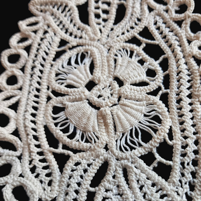 Close-up of intricate lace fabric with a floral design in Transylvanian style on a dark background