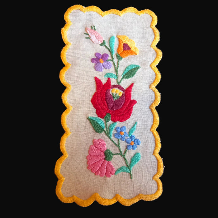 Embroidered floral linen vintage hungarian kalocsai with scalloped edge on a dark background