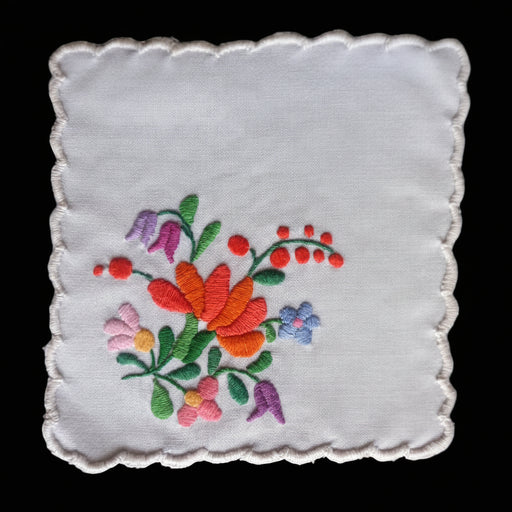 Vintage Hungarian Kalocsa Embroidered floral design on a white fabric square with a dark background